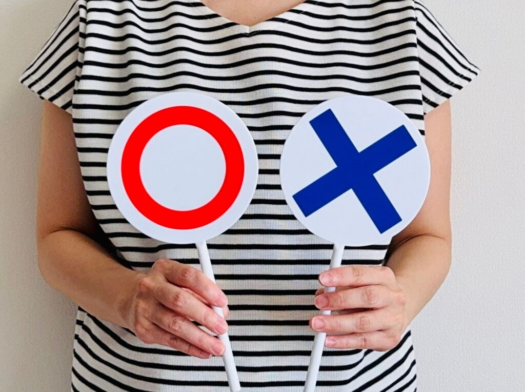 マルとバツを持っている女性の画像