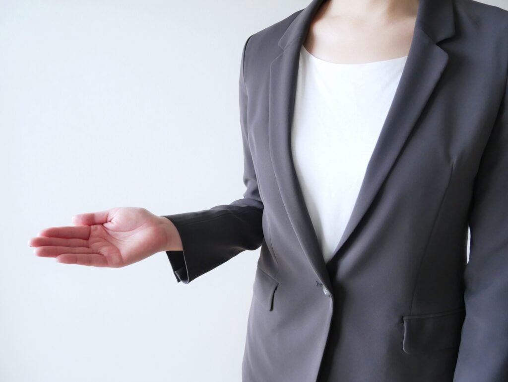 スーツを着た女性が手を差し伸ばしている画像