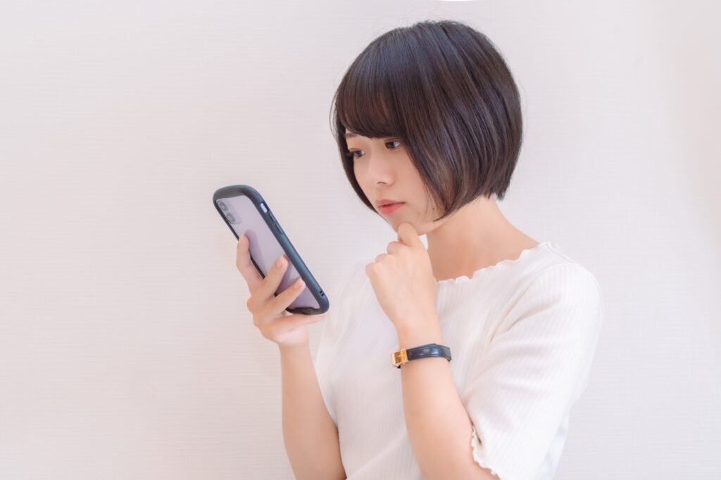 スマホを見て悩む女性の画像