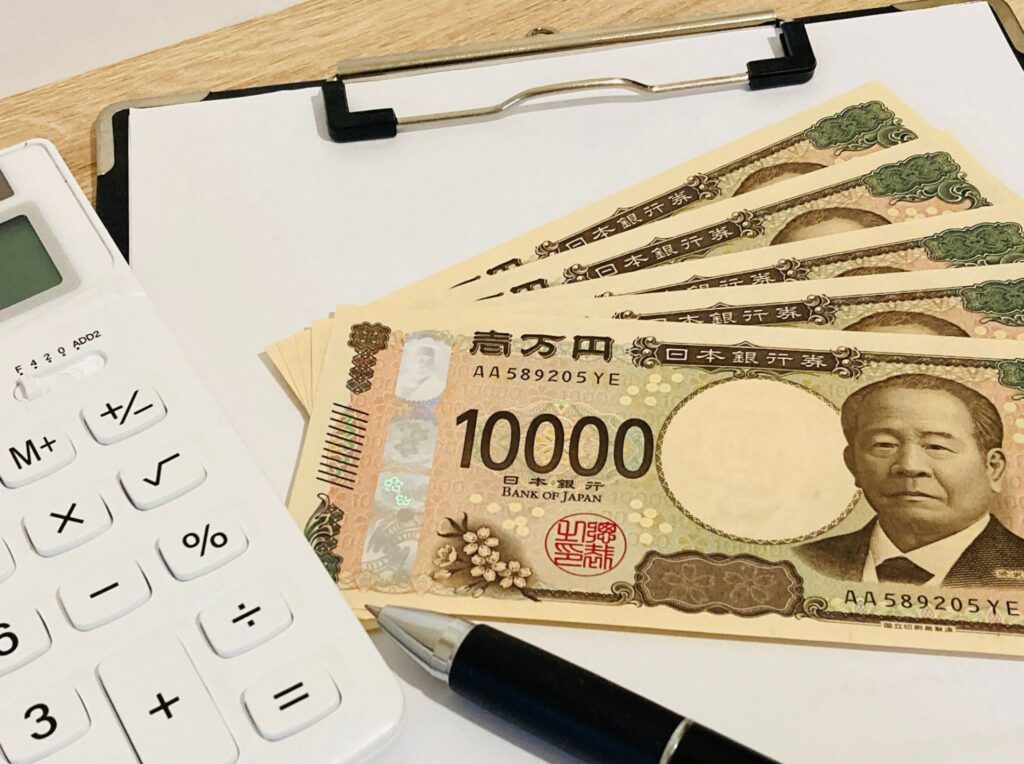 バインダーの上に置かれたお金と電卓の写真