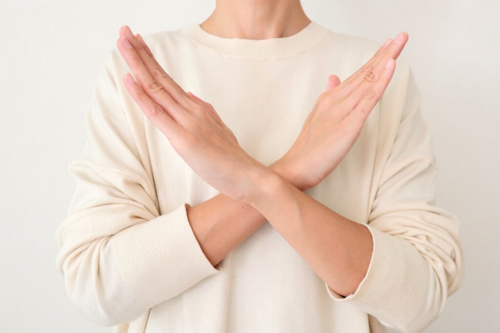 手でバツをつくる女性の画像