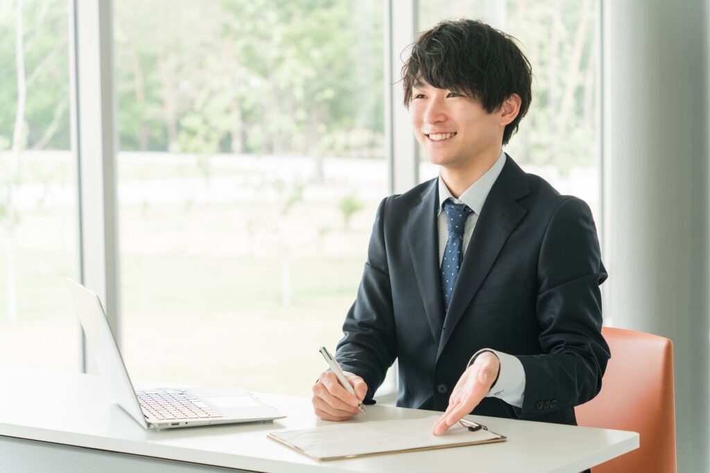 書類を使い案内する若い男性ビジネスマンの画像
