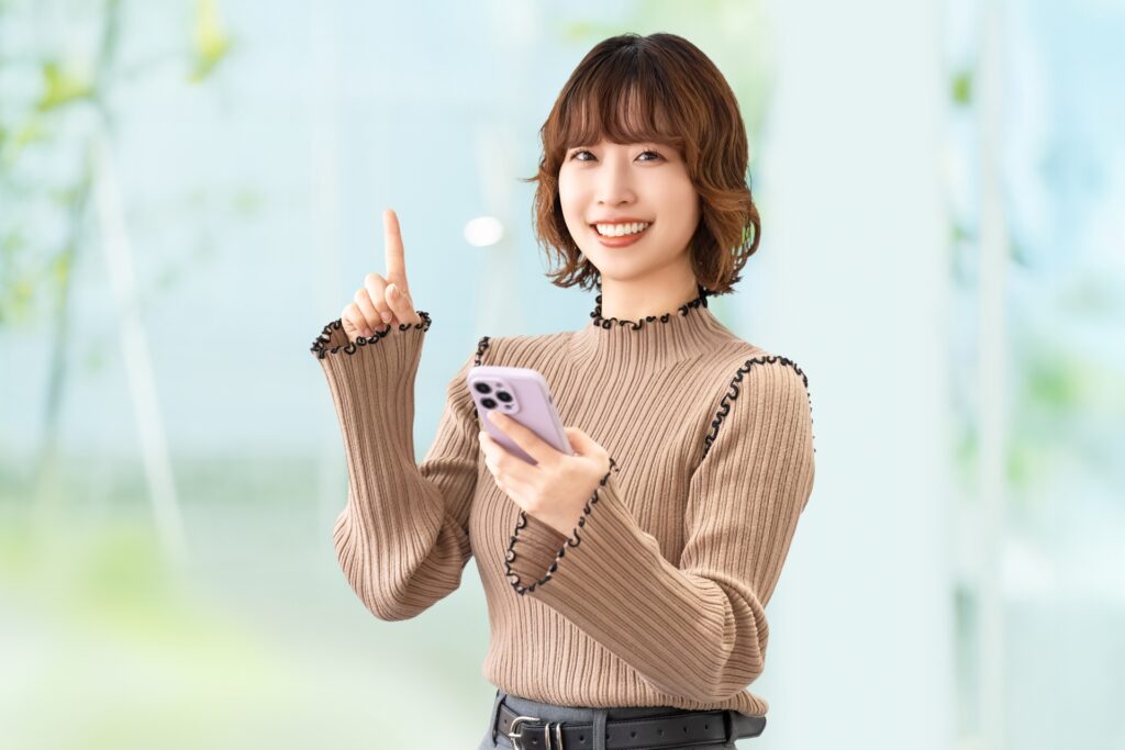スマホを持って案内をする笑顔の女性
の画像