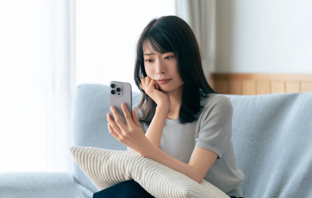 スマホを見ながら考えごとをする女性
の画像