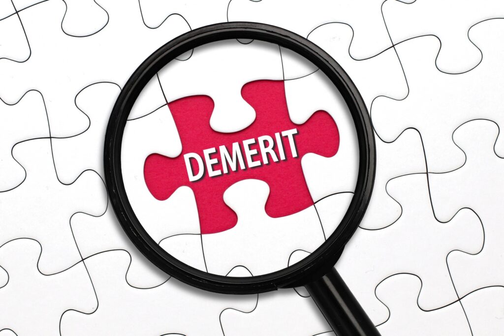 DEMERITという文字を虫眼鏡で見ている画像